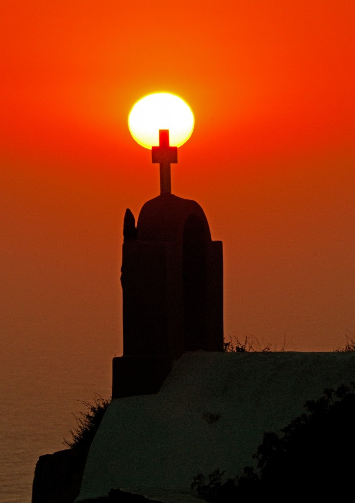 Sunset with silhouette of church cross in foreground, Oia, Santorini 
