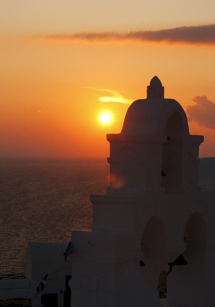 Sunset over Aegean Sea with chuch in foreground, Oia, Santorini, Greece