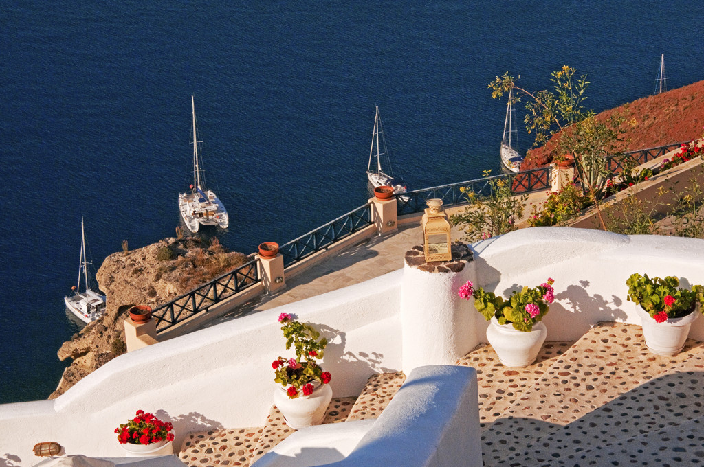 Stairway with plants and sailboats anchored off the coast, Oia, Santorini, Greece