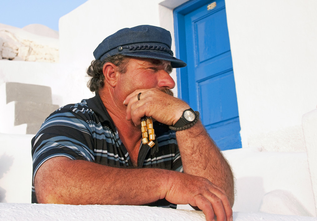 Greek man with prayer beads looking out to Aegean Sea, Oia, Santorini, Greece